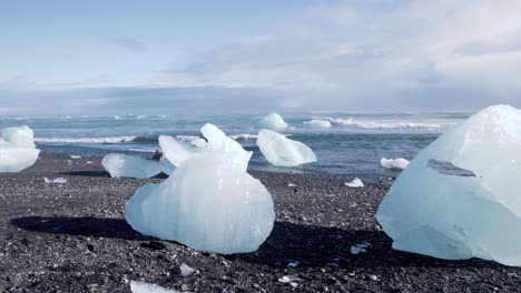Ice-chunks-on-Diamond-beach-in-Iceland-melting-in-the-Sun,-sea-waves