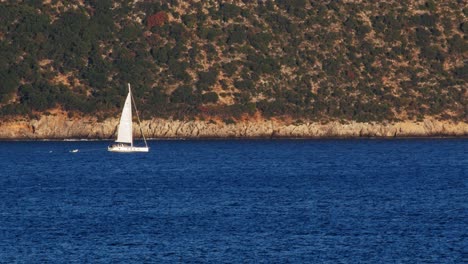 White-Sailboat-On-Blue-Ocean-Beach-In-Kefalonia,-Greece---wide-shot