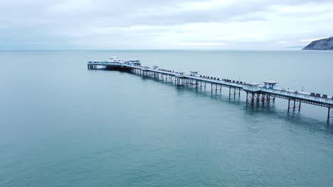 Llandudno-pier-historic-Victorian-wooden-boardwalk-seaside-landmark-aerial-view-slow-descend-right