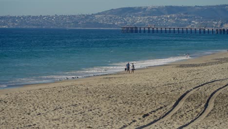 A-couple-walking-along-the-beach-together-in-San-Clemente,-California