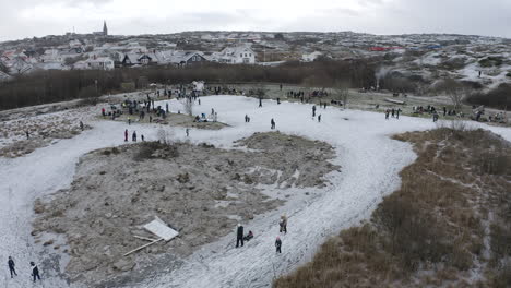 Drone-shot-of-people-and-families-ice-skating-with-his-ice-skates-at-Öckerö-Island-Municipality-in-Gothenburg-archipelago,-Sweden