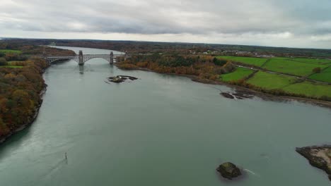 Beeindruckende-Luftaufnahme-Der-Hängebrücke,-Die-Die-Menai-Straße-Zwischen-Der-Insel-Anglesey-Und-Dem-Festland-Von-Wales-überquert