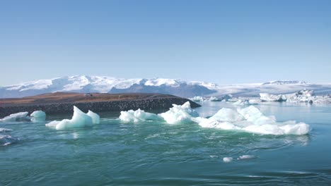 Water-flowing-around-icebergs-in-a-sea-lagoon-in-Iceland,-rocky-shores