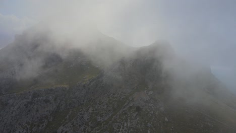 Sharp-pointy-mountains-revealing-theirselves-behind-a-cloud-of-mist-smoke-at-Sa-Calobra,-Mallorca,-Spain