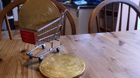 Golden-bitcoin-crypto-currency-coins-in-tiny-shopping-trolley-on-kitchen-table-concept-rotating-left-shot