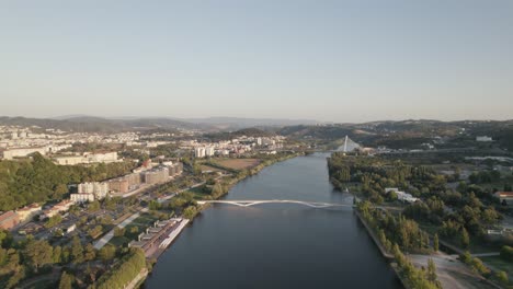 Fly-over-Mondego-river,-Coimbra-riverside-aerial-view,-Portugal