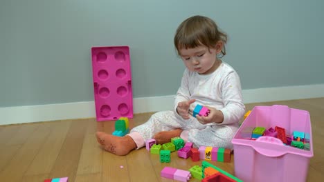 Little-baby-girl-playing-with-colorful-plastic-blocks-on-a-floor