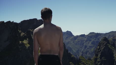 Shirtless-young-man-looks-out-over-beautiful-volcanic-mountain-range