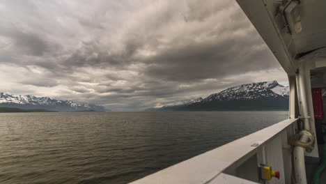 Ferry-Que-Viaja-A-Través-Del-Vasto-Océano-A-Oldvik-lyngen-Con-Vistas-A-Las-Pesadas-Nubes-Sobre-Montañas-Nevadas-En-El-Norte-De-Noruega