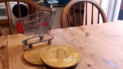 Golden-bitcoin-crypto-currency-coins-in-tiny-shopping-trolley-on-kitchen-table-concept-left-rotating-shot