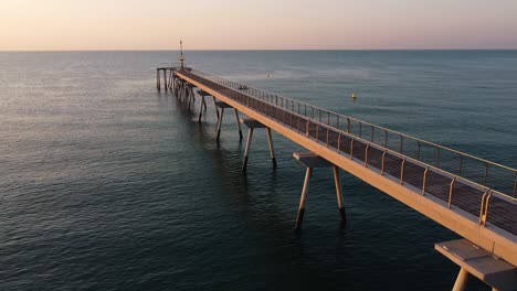 Amazing-shot-of-a-jetty,-flying-around-its-structure-creating-a-three-dimensional-perspective-of-its-architecture,-as-a-gentle-wind-blows-on-the-calm-water-during-twilight
