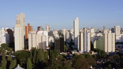 Beautiful-left-trucking-aerial-drone-shot-of-the-Pinheiros-district-in-São-Paulo-with-looming-skyscrapers,-apartment-buildings-and-groves-of-trees-on-a-warm-sunny-evening-in-Brazil,-South-America