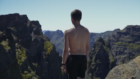 Young-man-stands-in-beautiful-mountains-of-Madeira-Portugal,-slow-motion