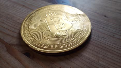 Wrapped-chocolate-gold-bitcoin-crypto-currency-concept-on-wooden-kitchen-table-left-orbit-looking-down