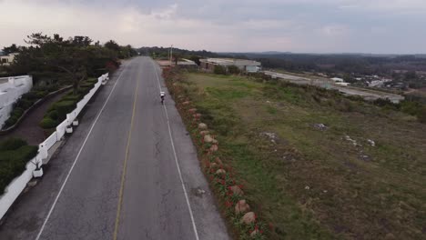 circular-drone-flight-over-an-ascending-asphalt-road-with-a-cyclist