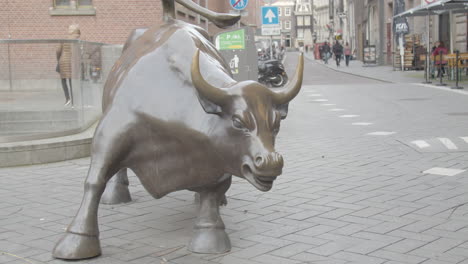 Close-up-of-the-bull-in-front-of-the-Amsterdam-Stock-Exchange-with-people-walking-in-the-background