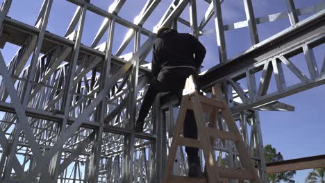 4k30-Hombre-Parado-En-Una-Escalera-Construyendo-Una-Casa-De-Estructura-De-Acero