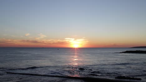 Erstaunlicher-Sonnenuntergang-über-Dem-Meer-Mit-Surfern-Und-Booten