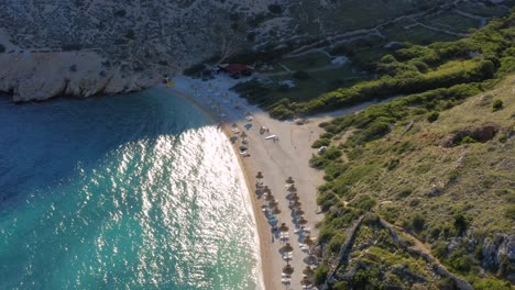 Aerial-dolly-shot-backing-up-along-the-coastline-of-an-isolated-beach-on-Krk-Island,-Croatia
