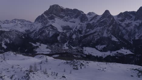 Aerial-forward-shot-of-snowy-winter-landscape-with-mountains-during-blue-hour-in-the-morning---Dolomites,Italy