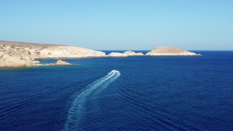 Aerial-shot-follow-Powe-rboat-sailing-on-Mediterranean-blue-sea,-Ios-Island