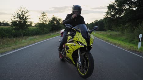 Confident-Man-Motorcyclist-Closing-Visor-on-Helmet-Sitting-on-Sport-Motorcycle-At-sunset