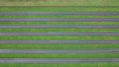 Overhead-Shot-Of-Parallel-Lines-Set-Of-Solar-Panels-Built-On-Green-Grass-Field