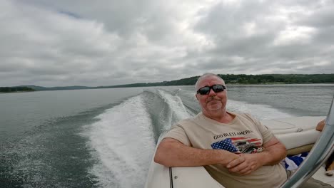 Man-enjoying-sitting-in-back-of-sports-boat-cruising-on-Table-Rock-Lake-in-the-Ozark-Mountains-of-Missouri-USA