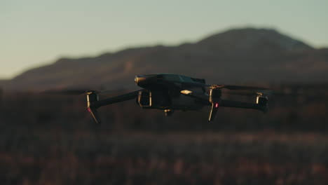 Modern-Quadcopter-Hovering-Over-Fields-With-Bokeh-Mountains-Background