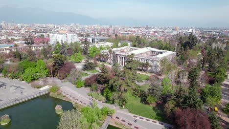 Aerial-view-of-Quinta-Normal-park-with-the-museums-and-the-city-of-Santiago-in-the-background,-sunny-day,-Chile