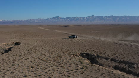 Film--Und-Tracking-Drohnenaufnahme-Eines-Autos,-Das-Durch-Die-Charyn-Schlucht-In-Kasachstan-Fährt