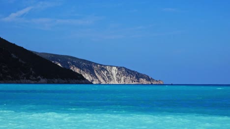 Perfect-blue-calm-waves-by-the-Agia-Kiriaki-Beach-and-mountains-in-Greece--Wide