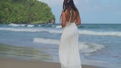 Descending-camera-movement-of-a-young-lady-in-a-white-dress-walking-on-the-beach