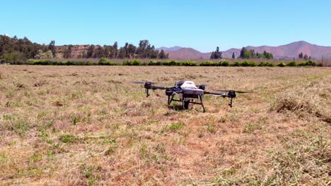 Agricultural-Drone-Taking-Off-and-Flying-Above-Agro-Fields-and-Clear-Sky-Mountains-near-Andean-Cordillera,-Smart-Farming-Field-Industry