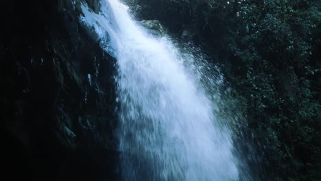 Tilt-down-close-up-view-from-below-a-waterfall-in-the-rainforest