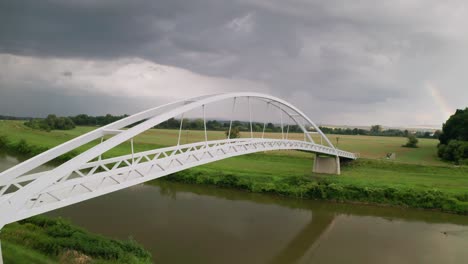 Flying-diagonally-through-a-cycling-bridge-running-across-calm-river-Moravia-in-Slovakia