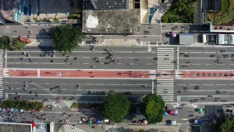Aerial-drone-top-down-bird's-eye-right-trucking-shot-of-the-famous-Paulista-Avenue-in-the-center-of-São-Paulo-with-giant-skyscrapers-surrounding-a-closed-off-street-with-crowds-of-people-walking