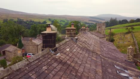 Drohne-Luftaufnahme-Des-Alten-Steinhauses-Schornstein-Und-Rauch-über-Dem-Dorf-Yorkshire