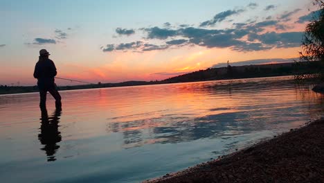 Ein-Mädchen,-Das-Nach-Sonnenuntergang-In-Einem-Wunderschönen-Ruhigen-See-Auf-Bass-Fischt