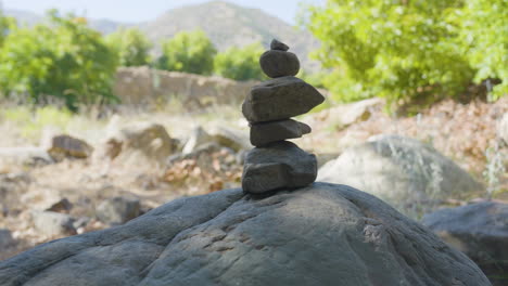 Panning-shot-of-Cairn-with-greenery-and-mountains-in-the-background-located-in-Santa-Paula-Punch-Bowls-Southern-California