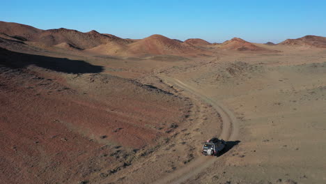 Cinematic-drone-shot-of-a-lone-car-traveling-in-the-Charyn-Canyon,-Kazakhstan