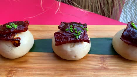 Mini-bao-buns-with-glazed-bacon-in-bbq-sauce-and-fresh-chives,-hot-Asian-steamed-buns-in-a-restaurant,-4K-shot
