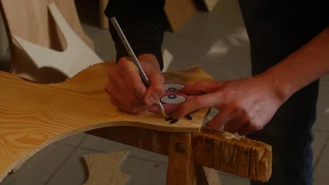 A-young-man-draws-a-figure-on-a-wooden-board-for-fretwork