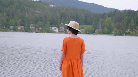 Mujer-Adulta-Con-Vestido-Naranja-Brillante-Caminando-Hacia-El-Lago