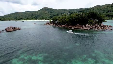 Aerial-view-of-white-boat-floating-next-to-rocky-island-off-the-coast-of-Praslin-The-Seychelles