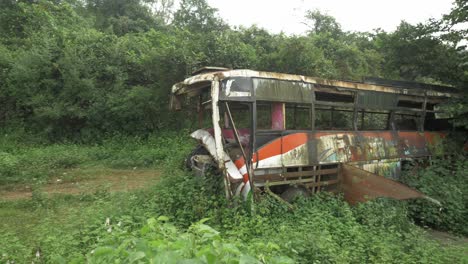 Pan-right-shot-of-damaged-and-abandoned-bus-dumped-beside-city-bypass-road,-Slow-Motion