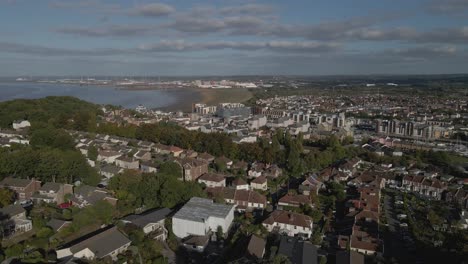 Aerial-view-of-Portishead-parish-near-Bristol,-drone-moving-forward-and-rotating-to-the-right-over-the-houses-blue-sky-on-the-background