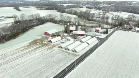 Aerial-of-rural-family-farm-in-USA-with-red-buildings-and-barns-during-snow-storm