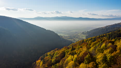 Lufthyperlapse,-Der-über-Berge-Fliegt,-Ein-Tal,-Das-Mit-Lebhaften-Herbstwäldern-Bedeckt-Ist