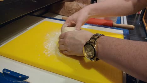 the-hands-of-the-worker-with-golden-watch-crushing-and-manipulating-wheat-flour-dough-to-prepare-baked-pizza-the-work-area-of-her-restaurant-business-,-Blocked-foreground,-Orders,-Galicia,-Spain